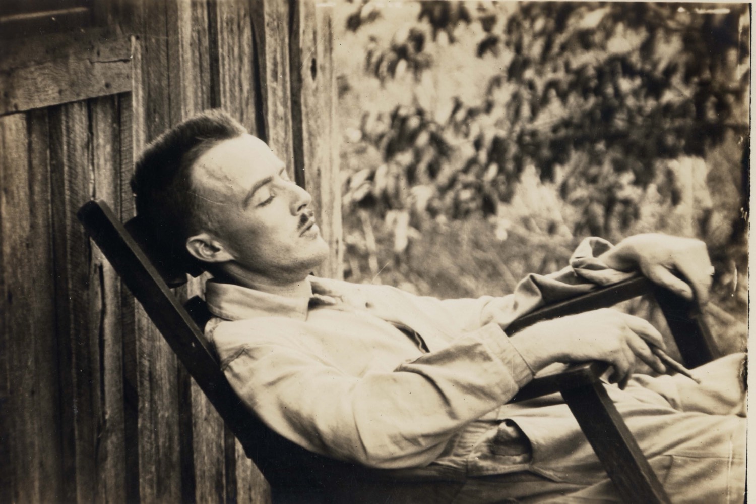 Vance Randolph asleep or listening in a wooden porch chair, mustache, a smoke in his hand
